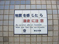 Tsunami warning sign on seawall in Kamakura, Japan, 2004. In the Muromachi period, a tsunami struck Kamakura, destroying the wooden building that housed the colossal statue of Amida Buddha at Kotokuin. Since that time, the statue has been outdoors.