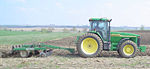 A modern John Deere 8110 Farm Tractor plowing a field using a chisel plow.