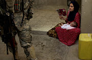 An Iraqi woman looks on as U.S. soldiers search her house in Ameriyah, Iraq. House searches by U.S. soldiers are a common occurrence in the Iraq war.