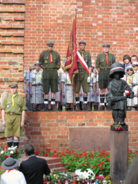 Statue of Mały Powstaniec (The Little Insurgent), just outside Warsaw's medieval city walls, commemorates the child soldiers that fought in the Warsaw Uprising. The boy wears a captured German helmet with Polish national colours. Honour guard of Polish Boy Scouts.