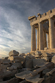The Parthenon from the south. In the foreground of the image, a reconstruction of the marble imbrices and tegulae (roof tiles) forming the roof is visible, resting on wooden supports.