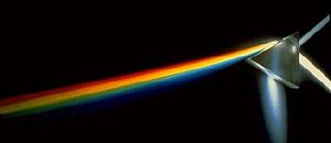 A beam of white light (entering upwards from the right) is dispersed into its constituent colors by its passage through a prism.  The fainter beam of white light exiting to the upper right has been reflected (without dispersion) off the first surface of the prism.