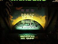 Mirrored holographic display and cardboard background of a Midway Space Invaders Deluxe arcade cabinet. Note the monitor on the bottom.