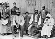 Tubman (far left), with Davis (seated, with cane), their adopted daughter Gertie (beside Tubman), Lee Cheney, John "Pop" Alexander, Walter Green, Blind "Aunty" Sarah Parker, and great-niece, Dora Stewart at Tubman's home in Auburn, New York circa 1887