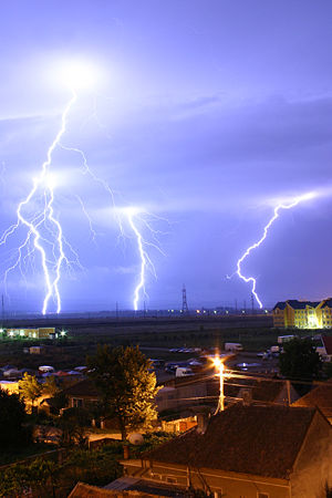 Lightning  is an example of plasma present at Earth's surface.  Typically, lightning discharges 30,000 amperes, at up to 100 million volts, and emits light, radio waves, x-rays and even gamma rays. Plasma temperatures in lightning can approach ~28,000 kelvin (~27,700oC) and electron densities may exceed 1024/m³.