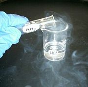 Hydrochloric acid sample releasing HCl fumes which are reacting with ammonia fumes to produce a white smoke of ammonium chloride.
