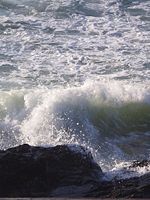 An ocean surface wave crashing into rocks