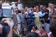 While under house arrest, Benazir Bhutto speaks to supporters outside her house.