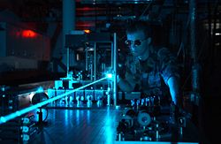 A military scientist operates a laser on an optical table.