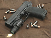 A Heckler & Koch USP .45 ACP handgun with a Surefire X200a Tactical Light, surrounded by hollow-point ammunition.