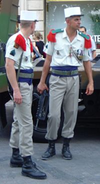 Légionnaires in dress uniform. Note the red epaulettes and the distinctive white kepi. They carry the standard assault rifle, the FAMAS.