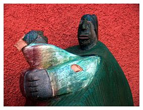 Small wooden sculpture depicting a Native American mother holding her child.