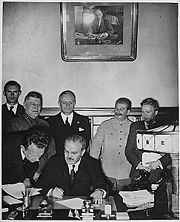Molotov signs the German-Soviet Non-aggression Pact. Behind him are Ribbentrop and Stalin.