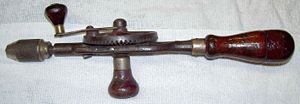 An old hand drill or "eggbeater" drill.  Note the hollow wooden handle, with screw-on cap, used to store drill bits.