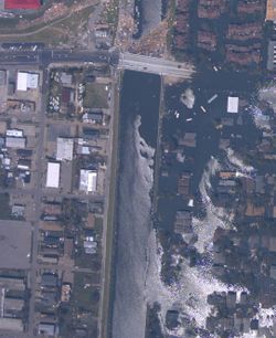 Breach in 17th Street Canal levee in New Orleans, Louisiana, on August 31, 2005, showing the inundated Lakeview neighborhood on the right and the largely dry Metairie side on the left.. (NOAA)
