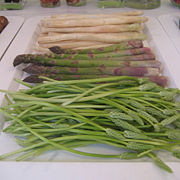 Three types of asparagus on a shop display, with white asparagus at the back and green asparagus in the middle. The plant at the front is Ornithogalum pyrenaicum, is commonly called wild asparagus, and sometimes "Bath Asparagus".