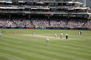 A Test match between South Africa and England in January 2005. The men wearing black trousers on the far right are the umpires. Test cricket, first-class cricket and club cricket are played in traditional white uniforms and with red cricket balls, while professional One-day cricket is usually played in coloured uniforms and with white balls.