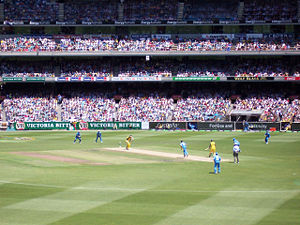 A One Day International match at The Melbourne Cricket Ground between Australia and India. The Australian batsmen are wearing yellow, while the fielding team, India, is wearing blue.