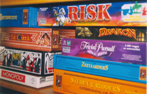 A shelf with several currently available board games. The left stack contains Carcassonne, La Città, Party & Co, and Monopoly. The right stack contains Risk, Drakon, Trivial Pursuit, The Seafarers of Catan, and Cities and Knights of Catan; some are of Dutch editions.
