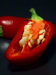 A ripe red jalapeño cut open to show the seeds