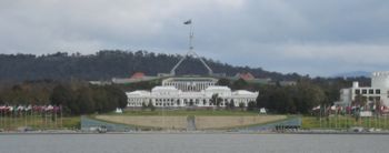 Two of Canberra's best-known landmarks, Parliament House and Old Parliament House (foreground). Commonwealth Place runs alongside the lake and includes the International Flag Display. Questacon is on the right