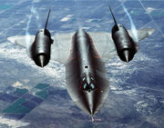 An air-to-air overhead front view of an SR-71A strategic reconnaissance aircraft. Note the water vapor, condensed by the low-pressure vortices generated by the chines outboard of each engine inlet.