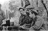 Listening to a Zenith Trans-Oceanic shortwave receiver are (seated from the left) Rogelio Oliva, José María Martínez Tamayo (known as "Mbili" in the Congo and "Ricardo" in Bolivia), and Guevara. Standing behind them is Roberto Sánchez ("Lawton" in Cuba and "Changa" in the Congo).