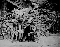 Children in the east end of London,  made homeless by the random bombs of the Nazi night raiders, waiting outside the wreckage of what was their home. September 1940 (National Archives).