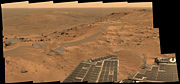 Spirit's "postcard" view from the summit of Husband Hill: a windswept plateau strewn with rocks, small exposures of outcrop, and sand dunes.  The view is to the north, looking down upon the "Tennessee Valley".  This approximate true-color composite spans about 90 degrees and consists of 18 frames captured by the rover's panoramic camera.