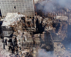 Portions of the outer shell of the North Tower lean against the remains of 6 WTC which suffered massive damage when the North Tower collapsed. The remains of 7 WTC are at upper right