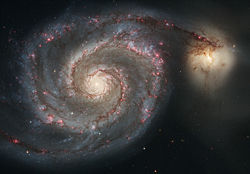 Strings of red H II regions delineate the arms of the Whirlpool Galaxy.