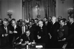 President Johnson signs the historic Civil Rights Act of 1964; (Martin Luther King stands just behind and slightly to the right of Johnson).