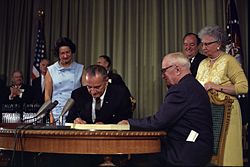 President Johnson signing the Medicare amendment; Harry Truman observes while Vice President Hubert Humphrey and Truman's wife, Bess, look on