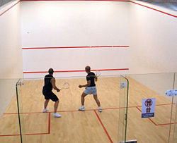 Players in a glass-backed squash court