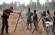 A French soldier, one of the international force supporting the relief effort for Rwandan refugees, adjusts the concertina wire surrounding the airport.