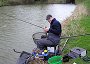 An angler on the Kennet and Avon Canal, England, with his tackle.