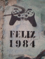 "Happy 1984" - Stencil graffito on the Berlin Wall remnant, in 2005. The image is of a DualShock video game controller.