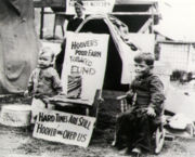 Children are sitting in front of sign that reads, "Hard Times Are Still Hoover-ing Over Us."