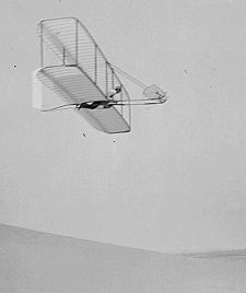 Wilbur Wright pilots the 1902 glider over the Kill Devil Hills, 10 October 1902. The single rear rudder is steerable; it replaced the original fixed double rudder. photo taken by Lorin Wright.
