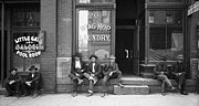 Men lounging outside saloon & Chinese laundry, 1910