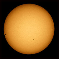 The sun photographed through a telescope with special solar filter. Sunspots and limb darkening are clearly seen at the image
