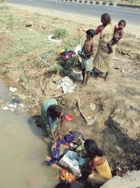 Women washing clothes in a ditch alongside a main road in Mumbai, India.