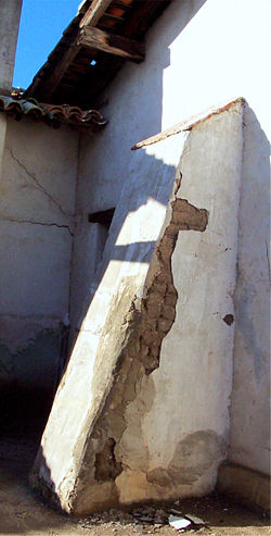 An original exterior wall buttress at Mission San Miguel Arcángel, which suffered extensive earthquake damage on December 22, 2003. Sections of the plaster finish coat have sloughed off, exposing the adobes beneath to the elements.