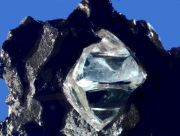 The slightly misshapen octahedral shape of this rough diamond crystal in matrix is typical of the mineral.
