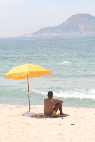Image:Man sitting under beach umbrella.JPG