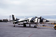 A Marine VMA-231 AV-8A with a camouflage paint during pre-flight operations. Harrier has two napalm bombs on its right wing.