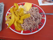 A dish containing gallopinto, tajadas, fried cheese and cabbage.