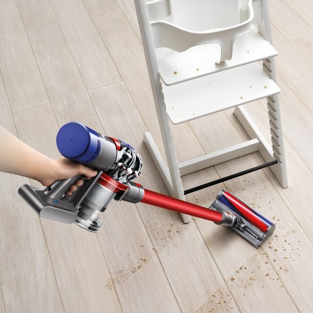 a dyson vacuum cleans a mess under a baby's high chair