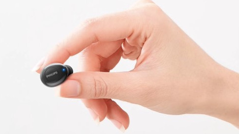 a hand holds one black earbud