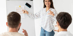 Instructor teaching sign language on a whiteboard to two students